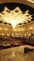 A grand lobby with a large chandelier, ornate columns, and plush seating areas.