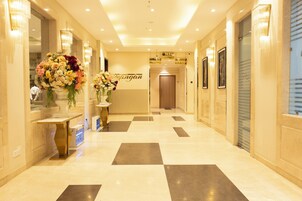 Un vestíbulo de hotel con piso a cuadros, una recepción y un gran arreglo floral.