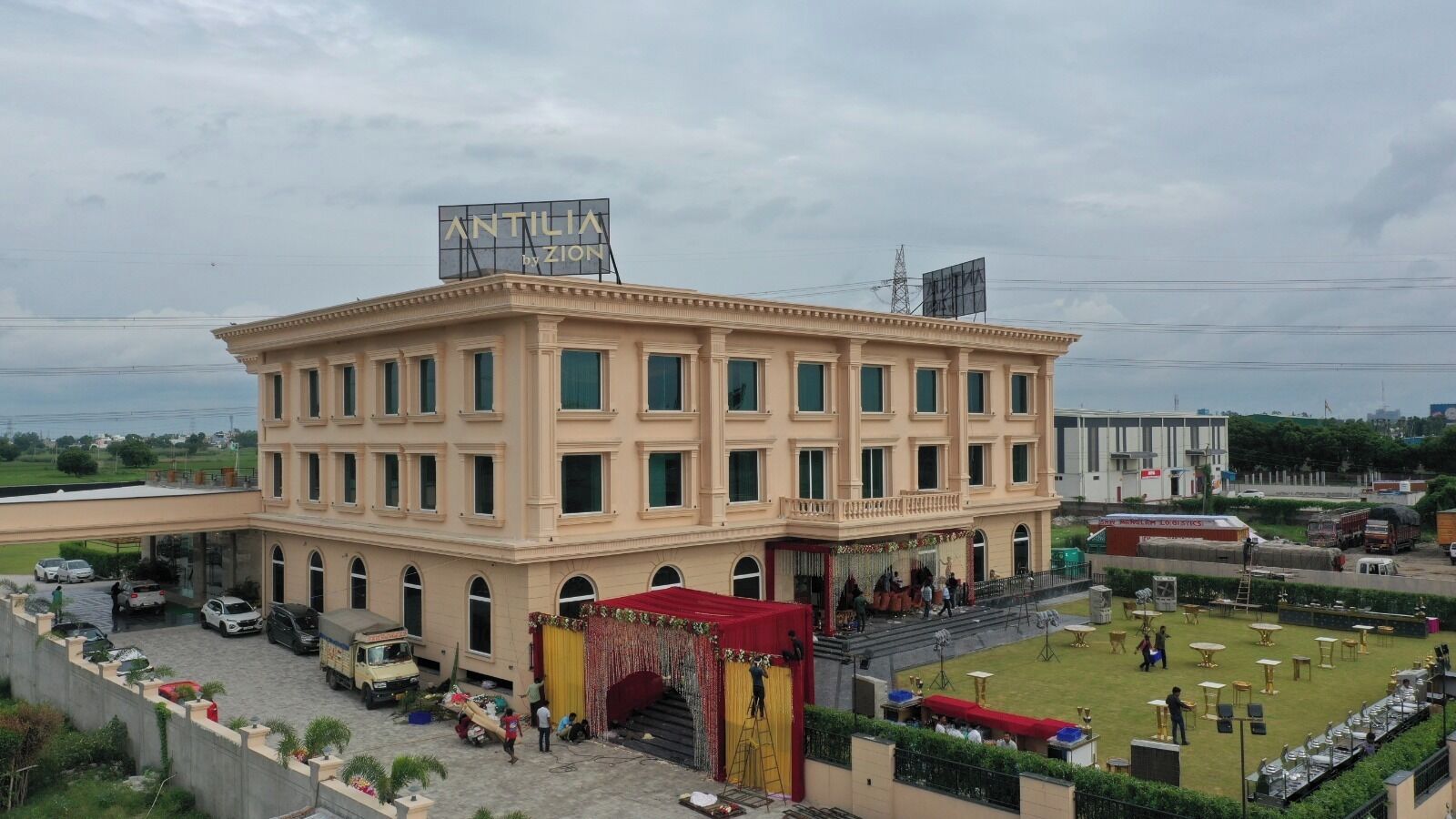 A multi-story building with a central courtyard, a covered area with a red canopy, and a billboard on the roof.