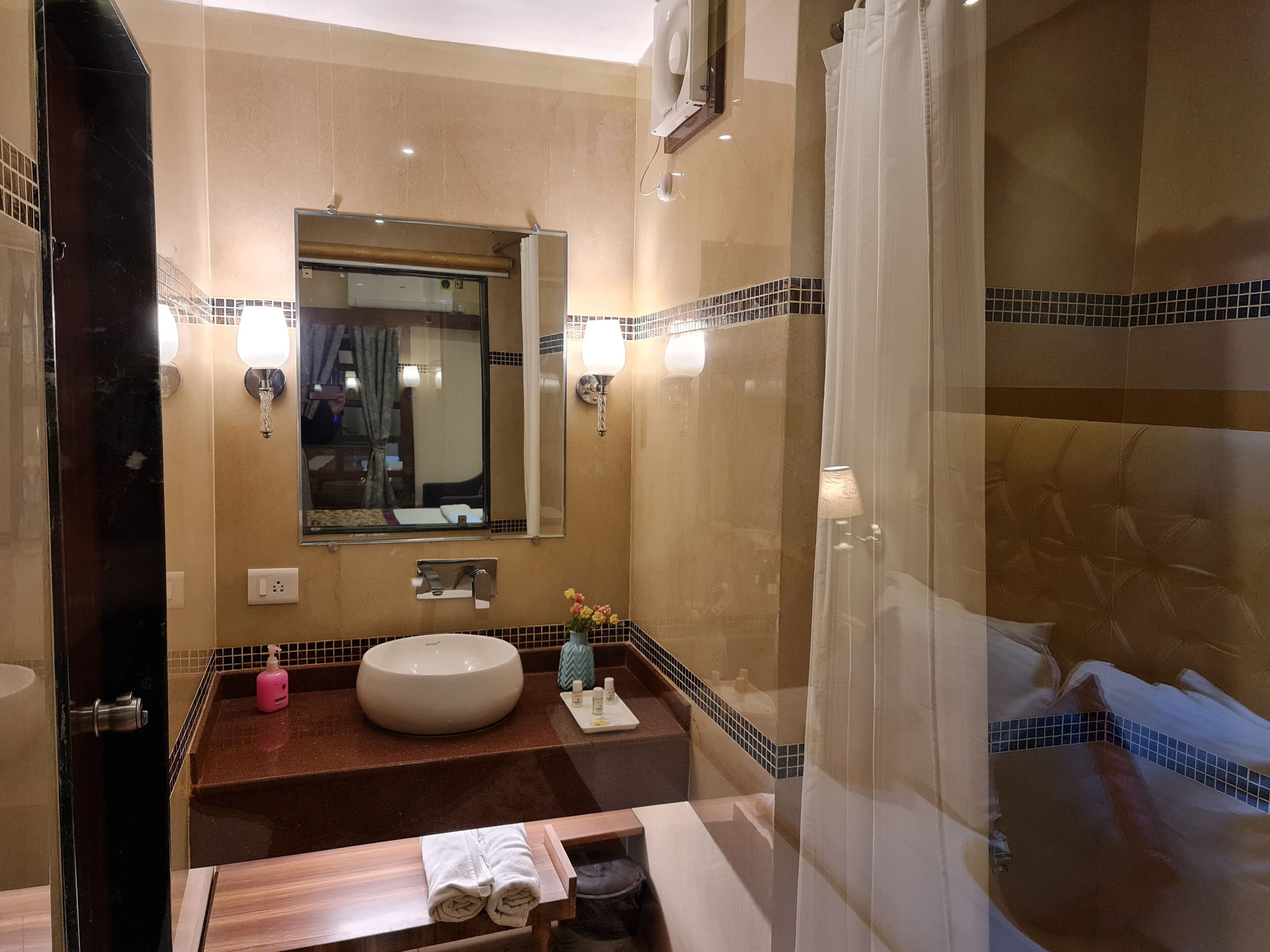 Uma casa de banho moderna com um espelho grande, uma pia redonda, toucador com espelho e zona de duche.