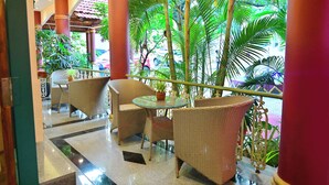 A lobby with wicker furniture, a glass table, and a potted plant. -  Woods Inn Resort (Airport Hotel) (Bhopal)