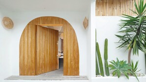 A wooden archway leading to a room with a bed and a hanging light fixture. - Villa Madissa by Villa Finder (Canggu)