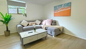 Un salon avec un canapé gris, une table basse blanche et un tableau accroché au mur.