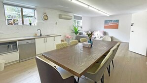 Une cuisine moderne avec des meubles blancs, un lave-vaisselle et un four à micro-ondes. On y trouve également un coin repas avec une table et des chaises en bois.