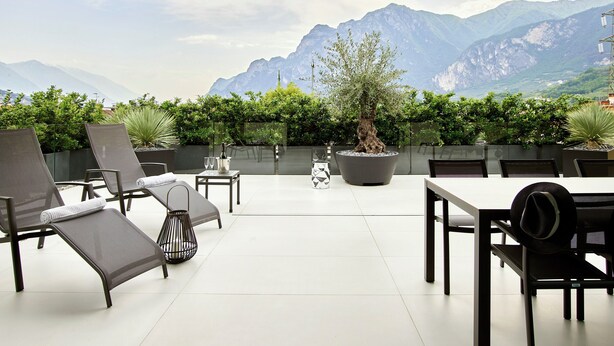 Une terrasse avec des sièges extérieurs, un pot de fleurs et une vue sur les montagnes.
