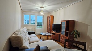 Una sala de estar con sofá, televisor, aparador y planta en maceta.