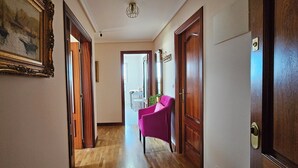 Un pasillo con puertas de madera, un cuadro enmarco y una silla rosa.