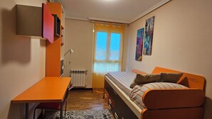 Una habitación pequeña con cama, escritorio y radiador.
