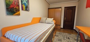 Un dormitorio con cama, armario, escritorio y puerta.