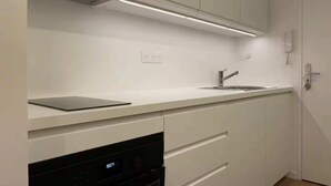 Una cocina moderna con armarios blancos, lavavajillas integrado y un lavamanos de acero inoxidable.