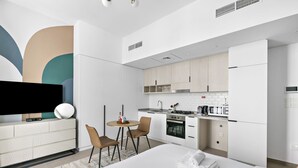 A modern hotel room with a bed, a TV, a dining area, and a kitchenette. - Silkhaus Belgravia Heights, JVC Dubai (Dubai)