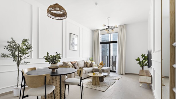 A modern living room with a round dining table, a sofa, and a TV on the wall. - Silkhaus Belgravia Heights, JVC Dubai (Dubai)