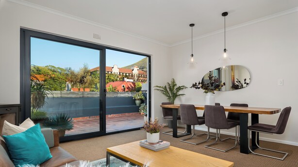 A modern living room with a sofa, coffee table, and dining area.