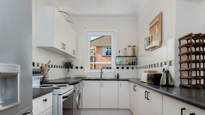 A modern kitchen with white cabinets, a stainless steel stove, and a wooden floor.