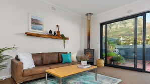 A living room with a brown leather sofa, a wooden coffee table, a large window with a view of cliffs, and a fireplace.