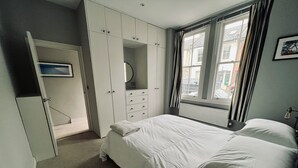 Un dormitorio con cama, armario y ventana con cortinas.