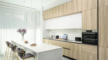 A modern kitchen with a central island, bar stools, wooden cabinets, and a built-in oven.