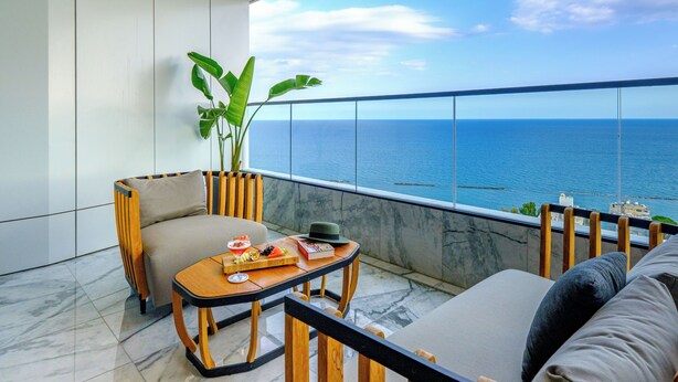 Un balcone con vista sul mare, un tavolo imbandito e posti a sedere.