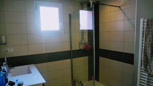 Un bagno con doccia vetro, lavabo con articoli da toilette e porta asciugamani decorato.
