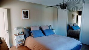 Una camera da letto con un letto grande, un comodino, una lampada, uno specchio e una ventola a soffitto.