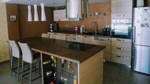 Una cucina moderna con isola centrale, elettrodomestici in acciaio inossidabile e luci a sospensione.