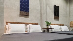 Een hotelkamer met twee bedden, een kleine tafel met een plant, en twee decoraties aan de muur.