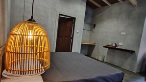 Een slaapkamer met een bed, een hanglamp, een houten deur en een plank met spullen.