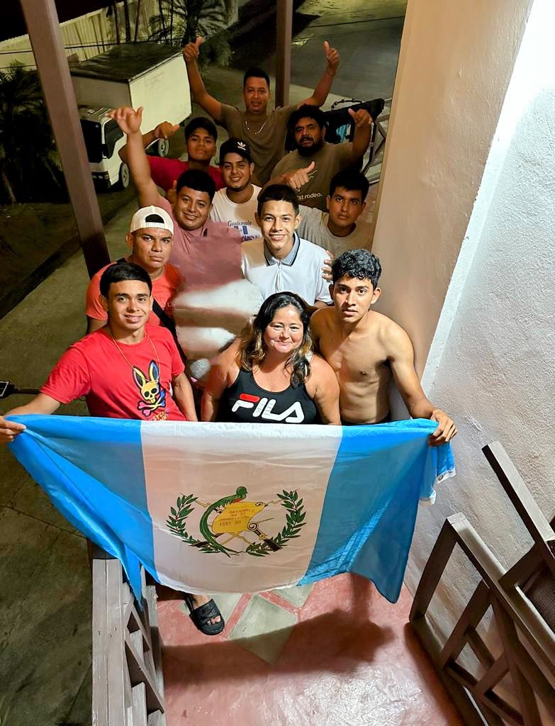 A group of people holding a flag, standing on a staircase in a building.
