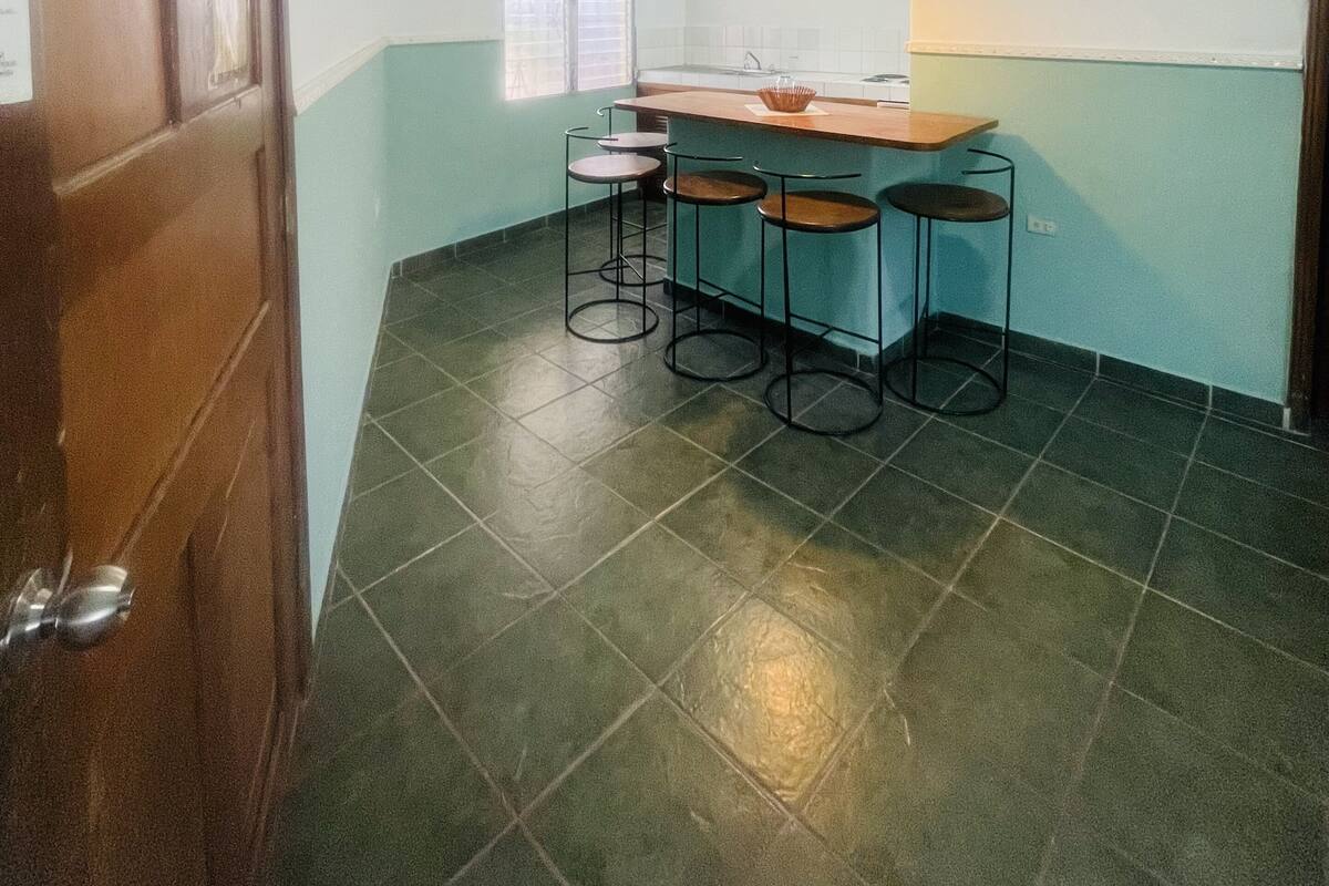 A kitchen with a bar area, a ceiling fan, and a window with blinds.