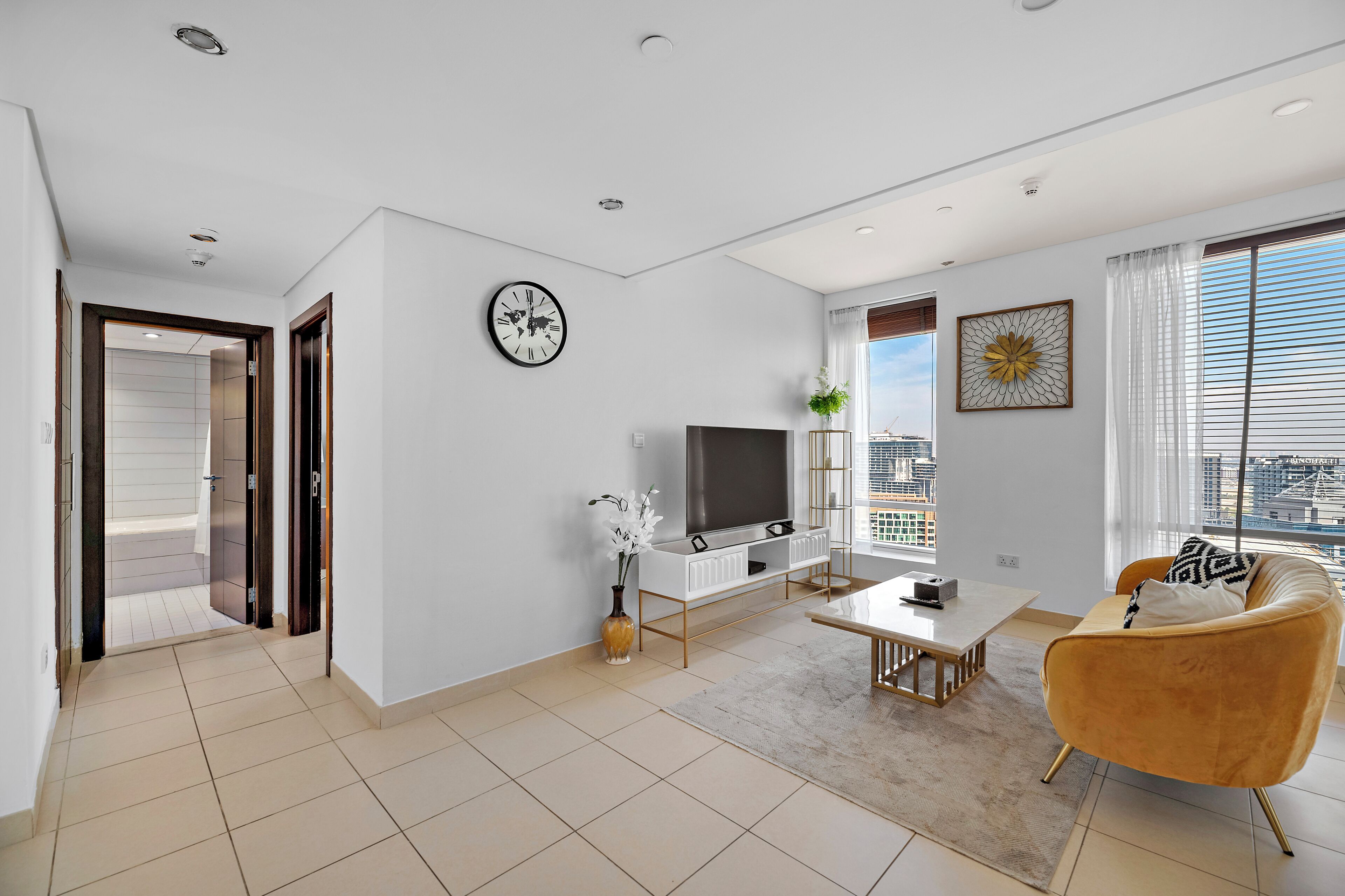 A modern living room with a TV, sofa, and a view of the city.