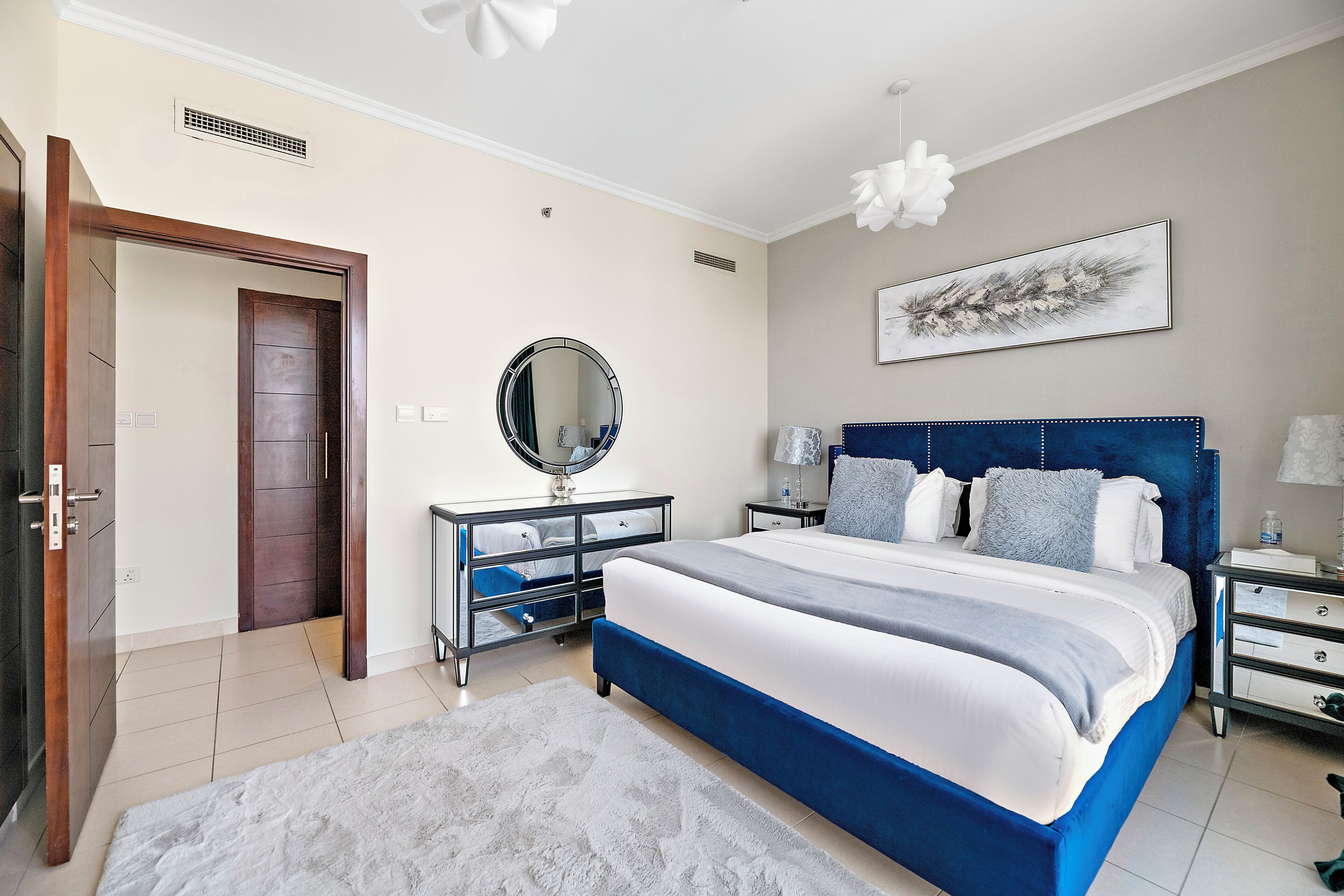 A bedroom with a large bed, a dresser, a mirror, and a nightstand.