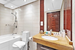 A modern bathroom with a bathtub, toilet, sink, and a large mirror. - Silkhaus Burj Views, Downtown Dubai (Dubai)