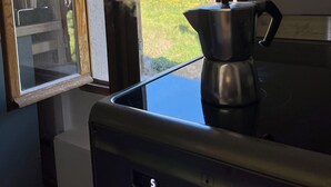 Une cuisine équipée d’une cuisinière, d’une machine à café et d’une fenêtre donnant sur un jardin.