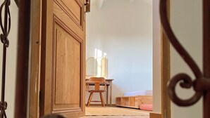 Une porte en bois qui donne sur une pièce où se trouvent une chaise et une petite table.