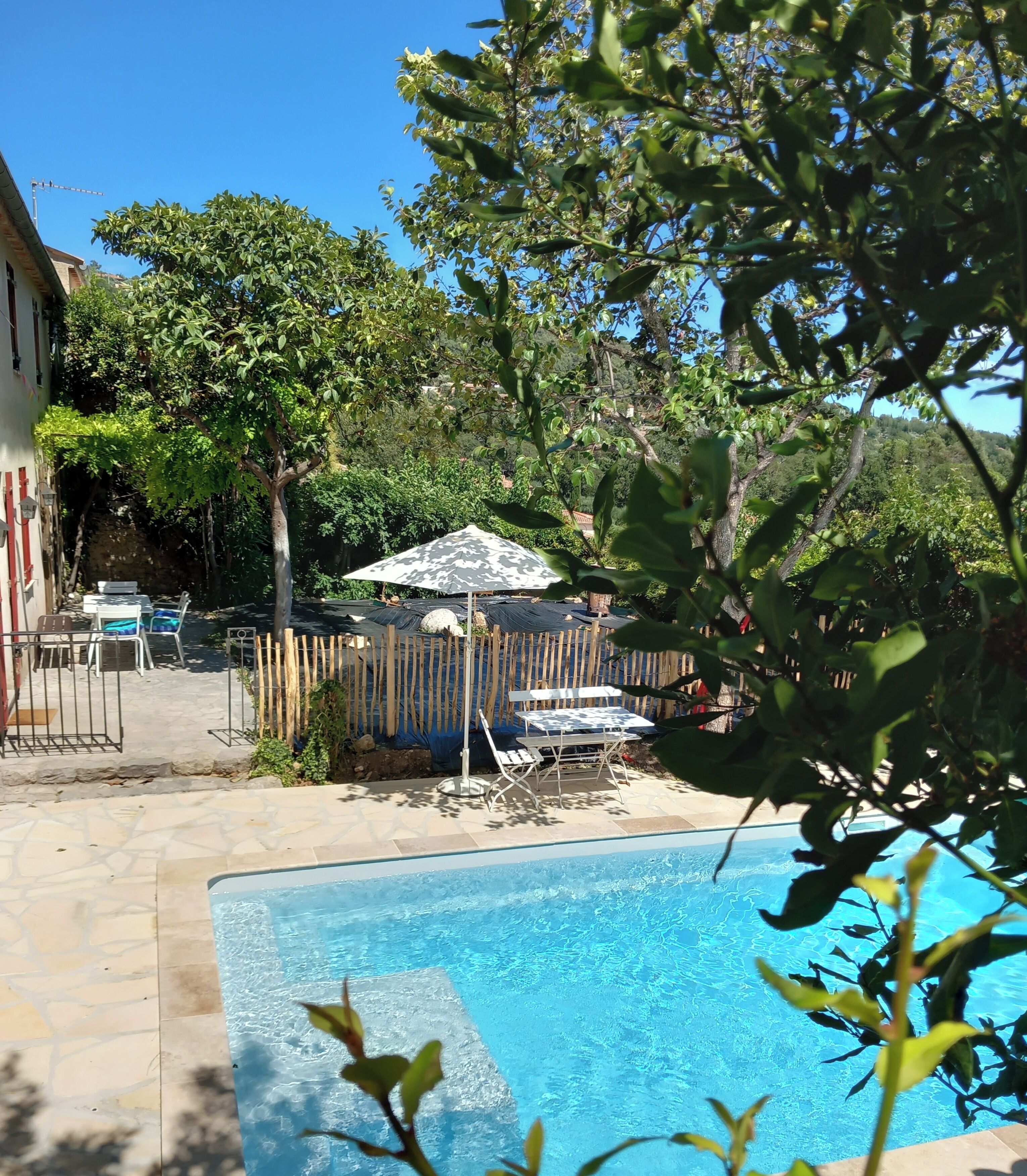 Un jardin avec une piscine, une clôture en bois et du mobilier d’extérieur.