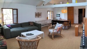 Un grand espace de vie comprenant un canapé, des fauteuils, une table basse et une table à manger.