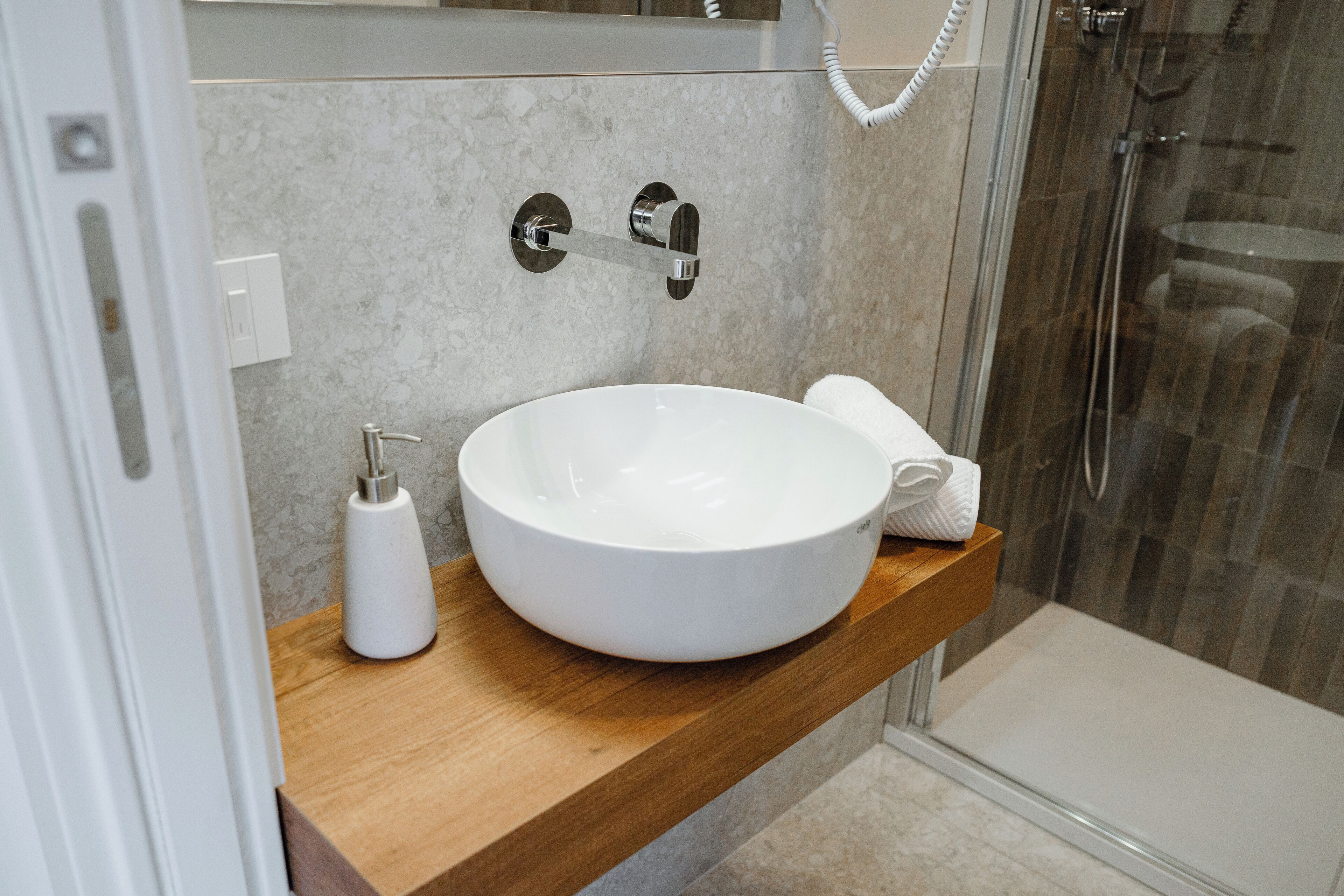 A bathroom with a white sink, wooden countertop, and a glass shower enclosure.