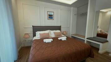 Een netjes ingerichte hotelkamer met een groot bed, nachtlampen, een klein bankje en een spiegel.