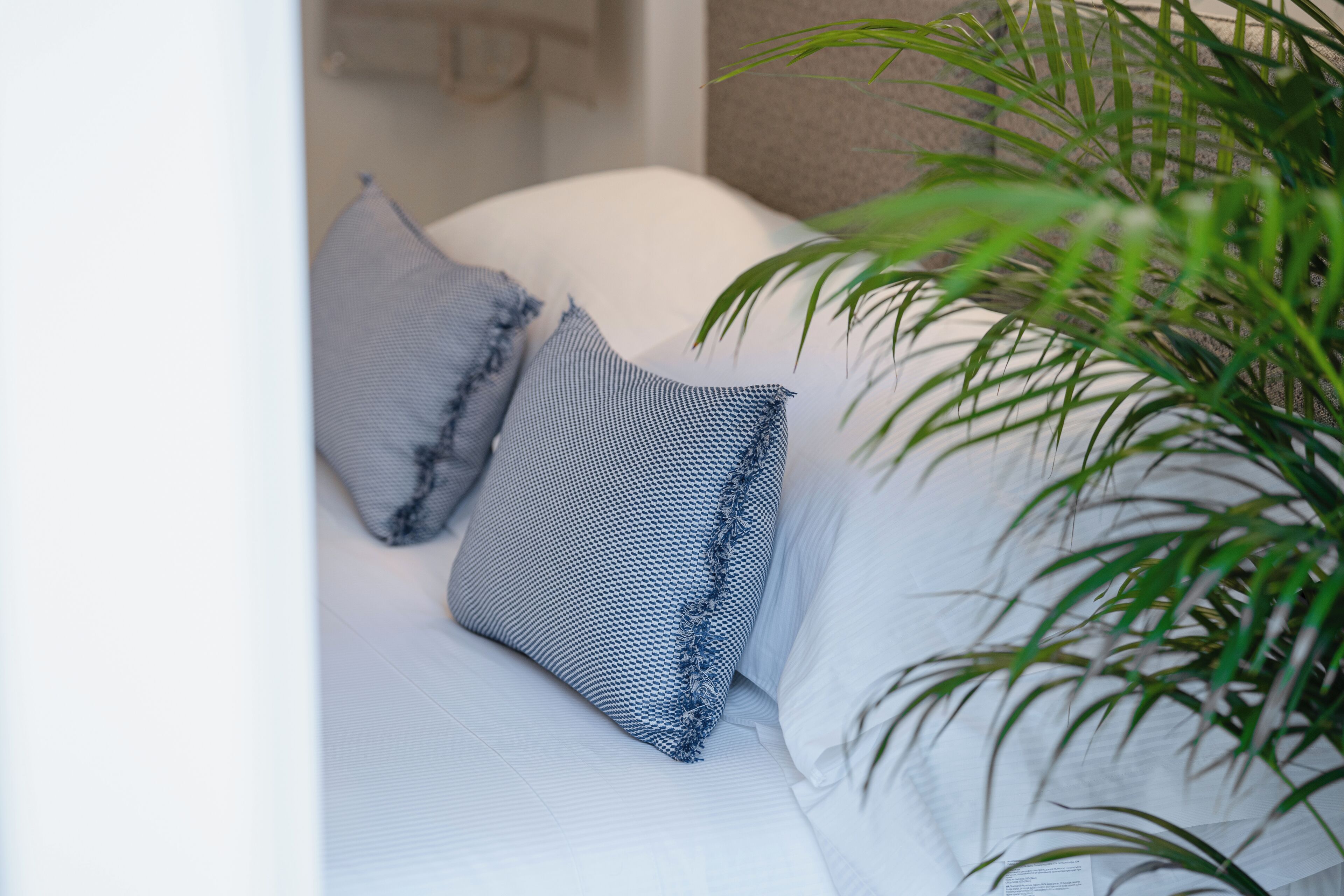 Una cama con ropa de cama blanca y dos almohadas, una con estampado azul y blanco y la otra completamente blanca.
