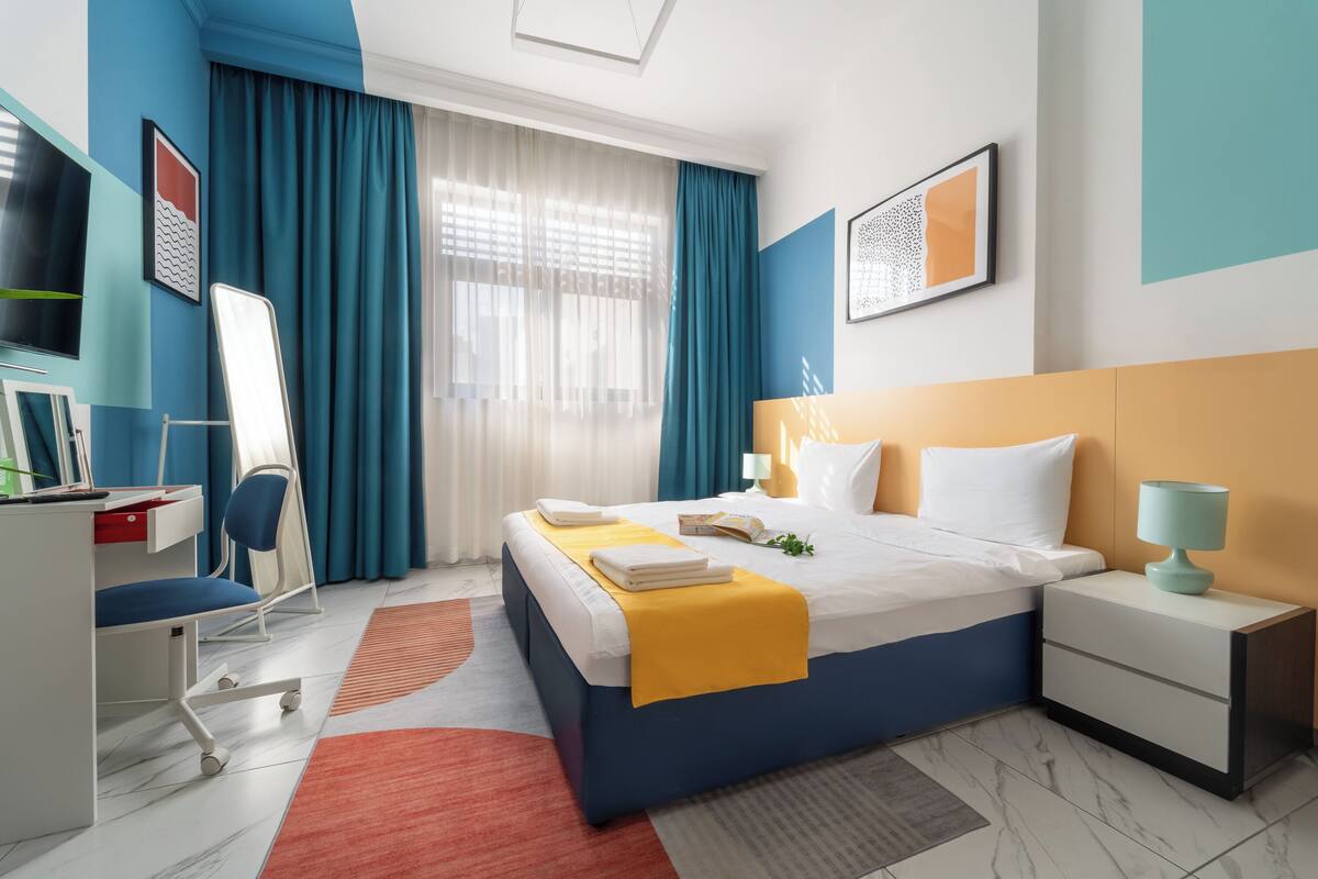 A modern hotel room with a large bed, a desk, and a chair.