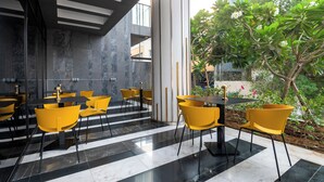 A modern indoor dining area with black and white tiled floors, yellow chairs, and black tables. - izzzi life Mint Holiday Home Apartments (Dubai)