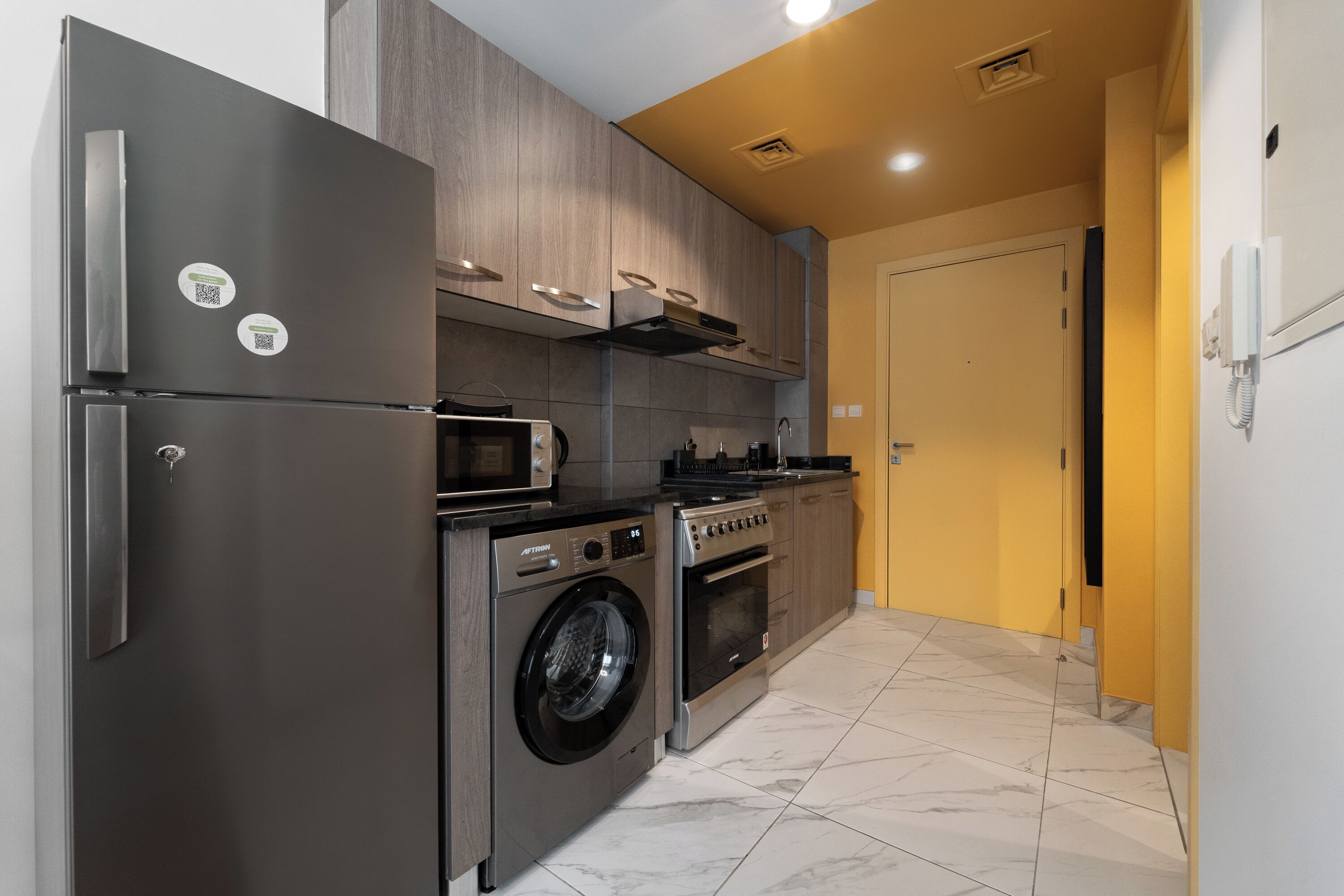 Een moderne keuken met roestvrijstalen apparatuur, een wasmachine en een magnetron.