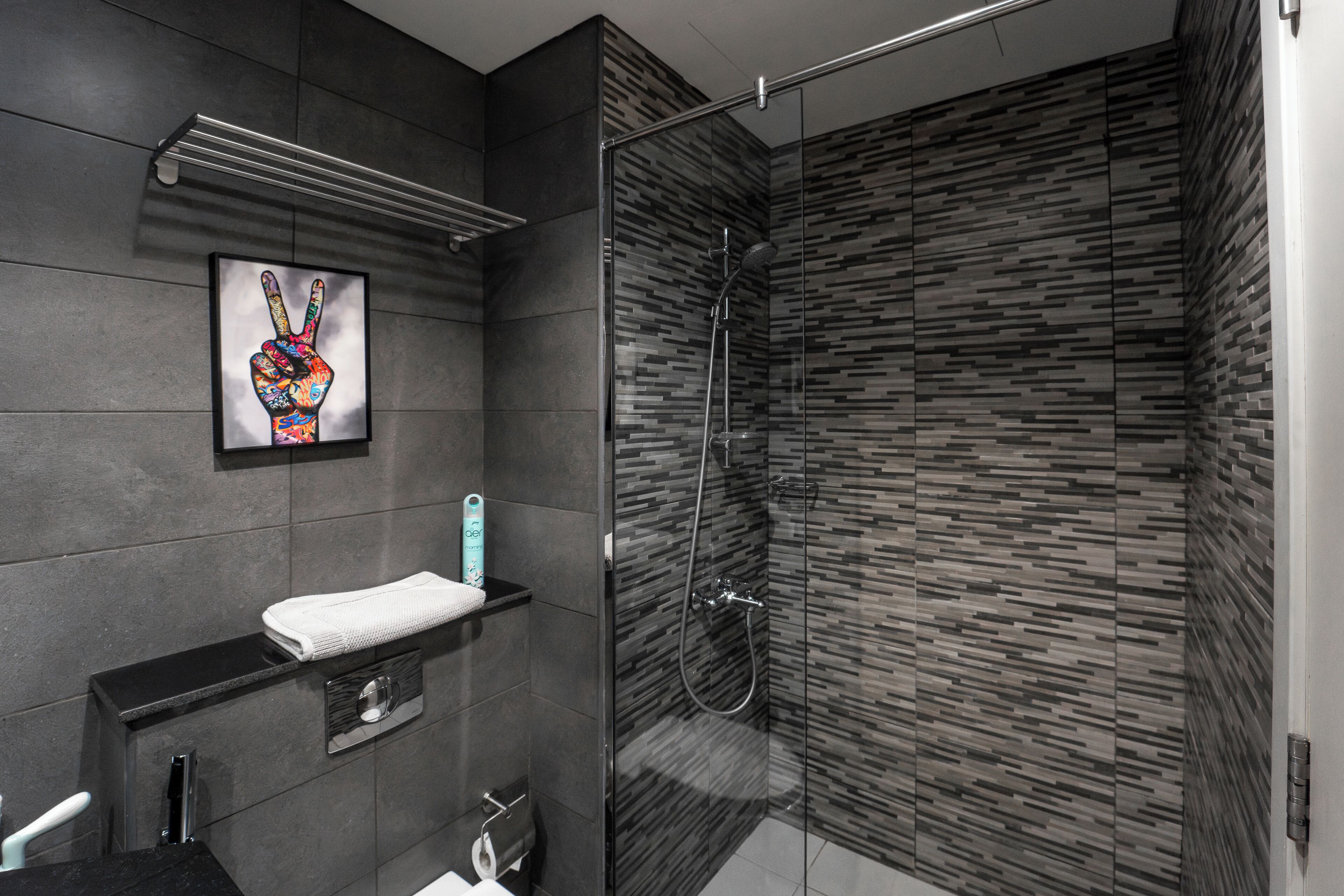 A modern bathroom with a glass-enclosed shower, a towel rack, and a framed artwork on the wall.