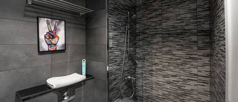 A modern bathroom with a glass-enclosed shower, a towel rack, and a framed artwork on the wall.