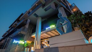 A modern building with a prominent 'iizzilife' sign, large columns, and a balcony. - izzzi life Mint Holiday Home Apartments (Dubai)