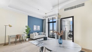 Ein modernes Wohnzimmer mit Essbereich, einer Couch, einem Schreibtisch und einem großen Fenster mit Blick.