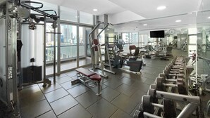Ein modernes Fitnessstudio mit verschiedenen Trainingsgeräten, großen Fenstern und Blick auf die Stadt.