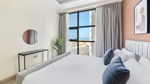 Ein modernes Hotelzimmer mit einem großen Bett, Blick auf die Stadt und einer Topfpflanze.