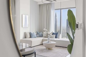 A modern living room with a sectional sofa, a round coffee table with a vase, and a large window offering a city view. - Silkhaus Downtown Views 2, Downtown Dubai (Dubai)