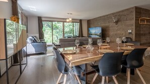 A modern dining area with a wooden table set for six, surrounded by dark chairs.